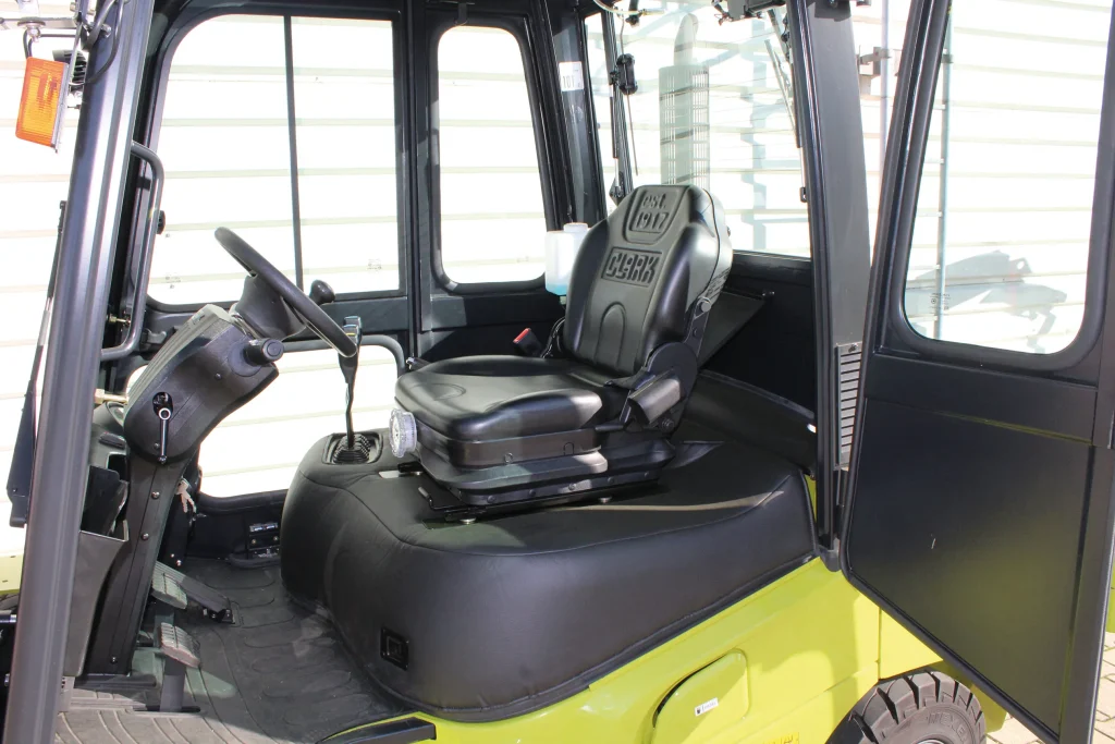 Interior de la cabina de la carretilla elevadora Clark con asiento ergonómico y controles de fácil acceso.