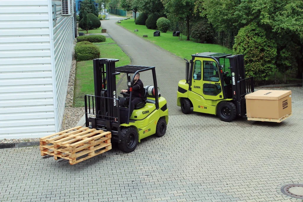 Dos carretillas elevadoras Clark GTS30 y GTS33 transportando mercancías en un entorno industrial.