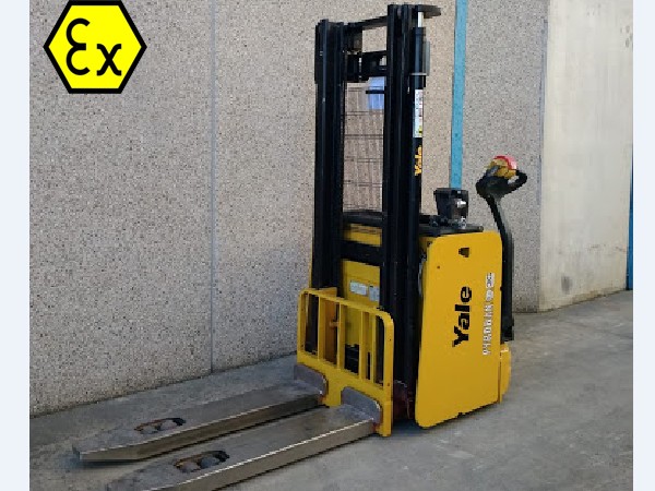 Apilador eléctrico Yale ATEX en vista semilateral junto a pared exterior, compacto y seguro para uso industrial.