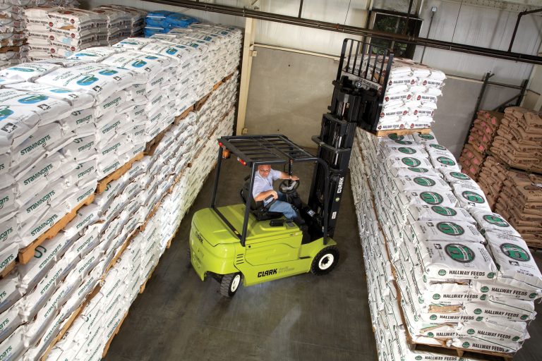 Carretilla elevadora con batería de plomo manejando pallets en un almacén estrecho