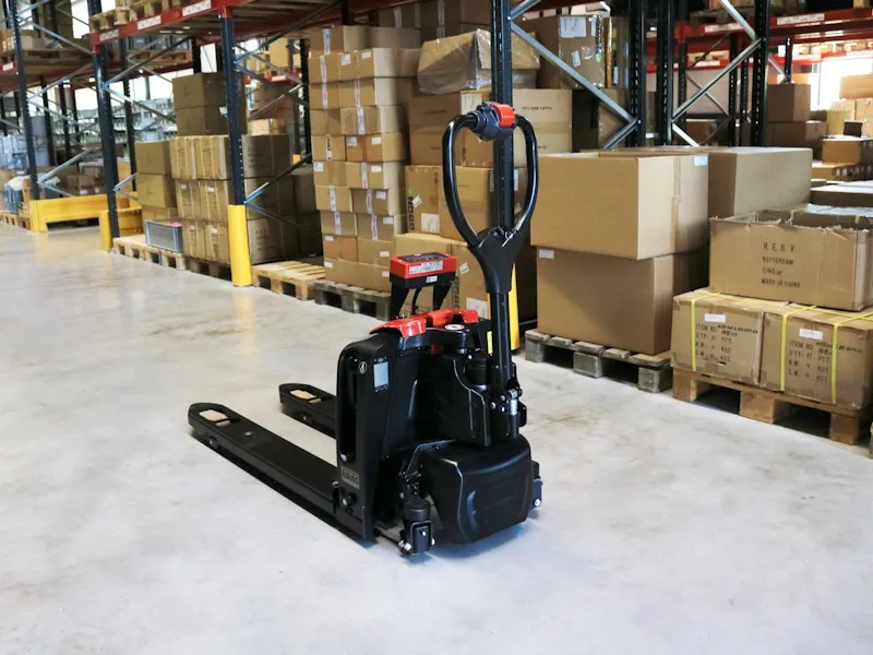 Transpaleta eléctrica RAVAS Ergo Truck-2 ubicada en un almacén con cajas apiladas.