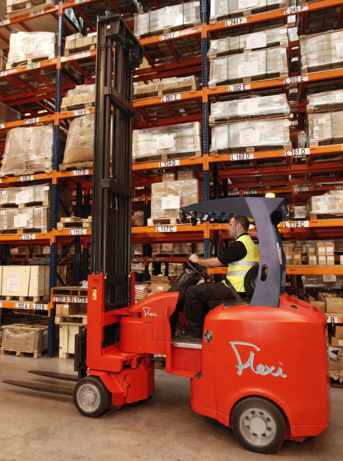 Carretilla elevadora Flexi StorMAX 25 articulada manejada por un operario, trabajando en un pasillo estrecho de un almacén con estanterías altas.