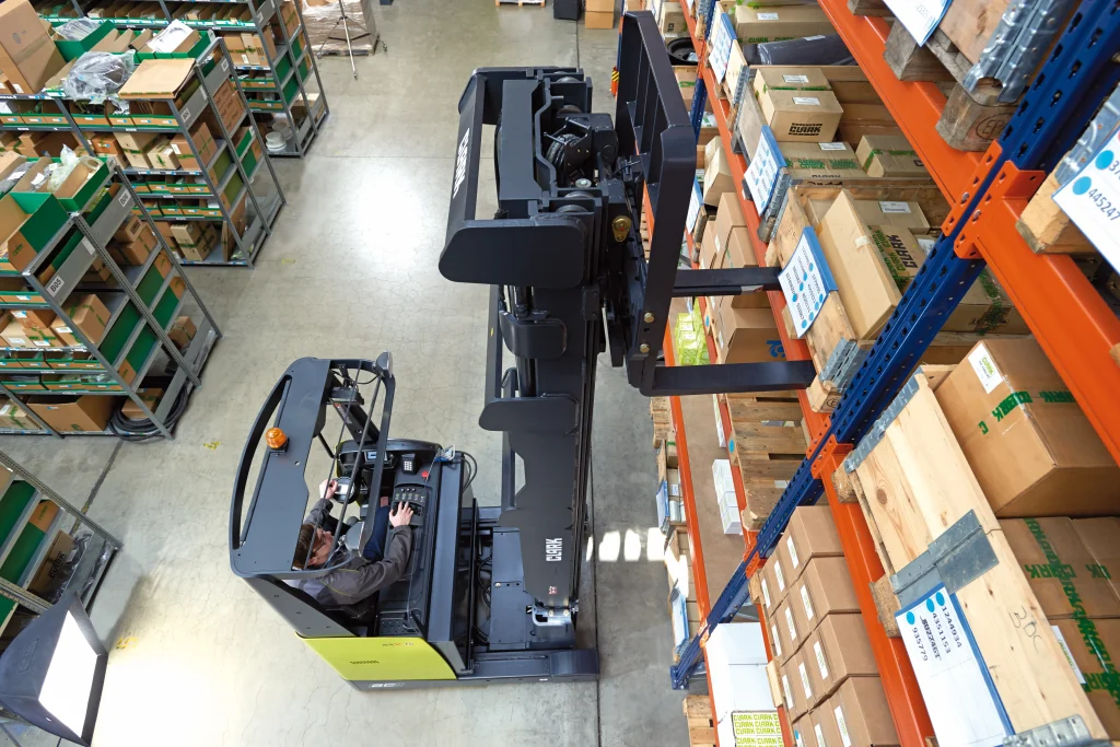 Vista superior de una carretilla retráctil Clark extrayendo una caja de una estantería alta en un pasillo de almacén