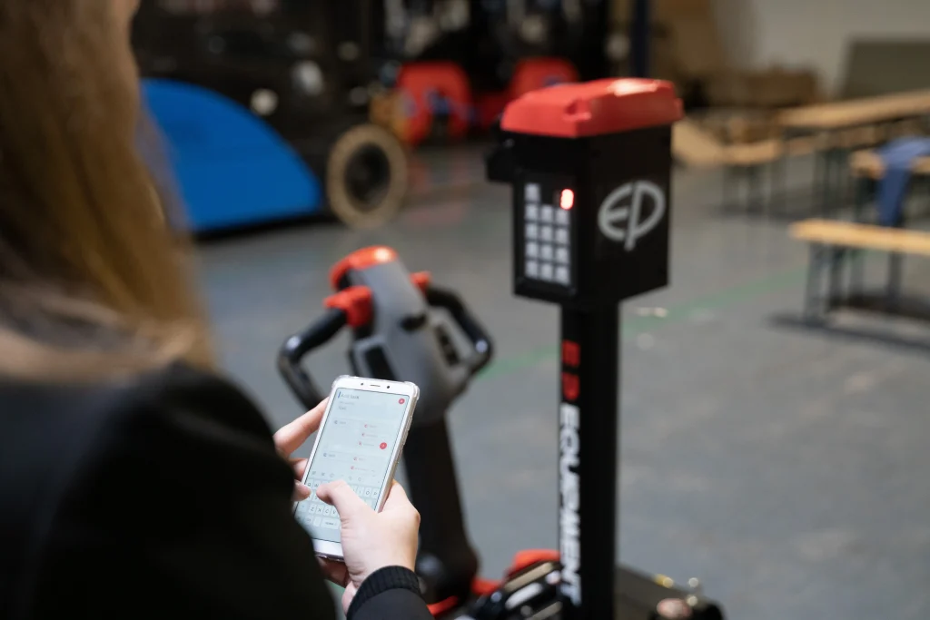 Persona programando tareas en una transpaleta eléctrica XP15 mediante una aplicación móvil.