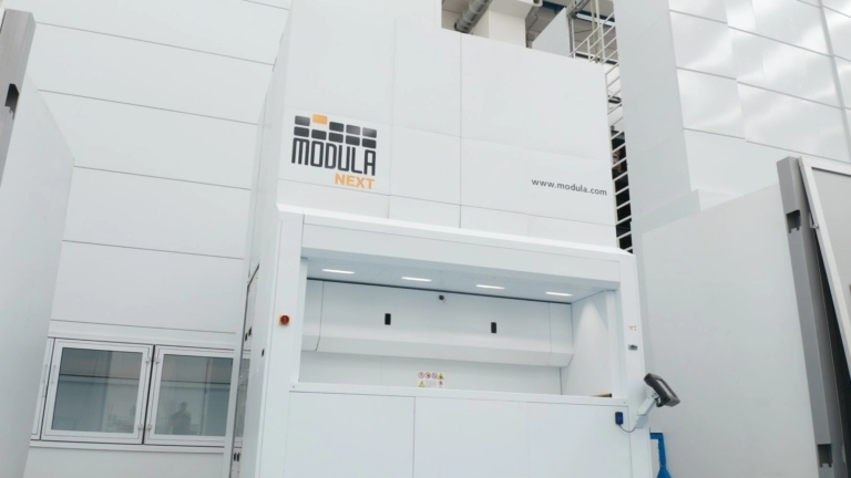 Sistema de almacenamiento vertical Modula NEXT instalado en un entorno industrial, mostrando su diseño moderno y funcional.