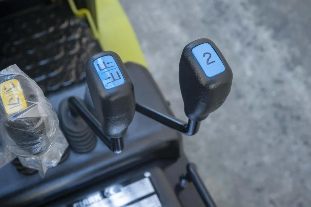 Primer plano de las palancas de control de una carretilla elevadora, mostrando los mandos ergonómicos para levantar y manejar las cargas.