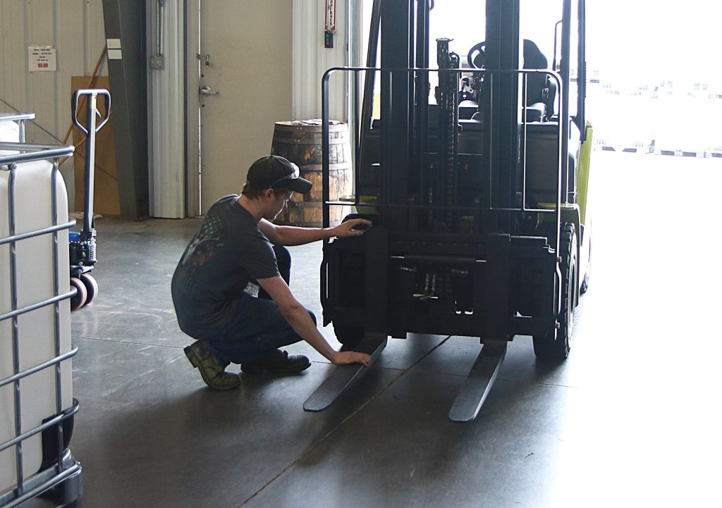 Técnico inspeccionando las horquillas de una carretilla elevadora CLARK Serie S en interior de almacén