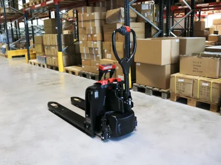 Transpaleta eléctrica RAVAS Ergo Truck-2 ubicada en un almacén con cajas apiladas.